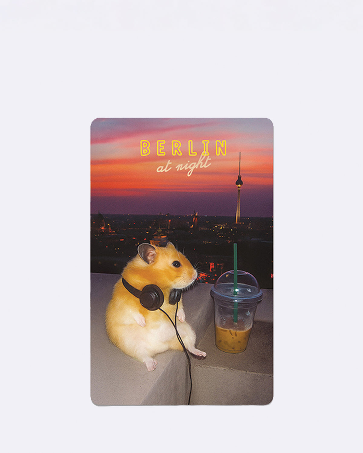 Postkarte mit Hamster und Kopfhörern vor Berliner Skyline im Sonnenuntergang mit Schriftzug "BERLIN at night"